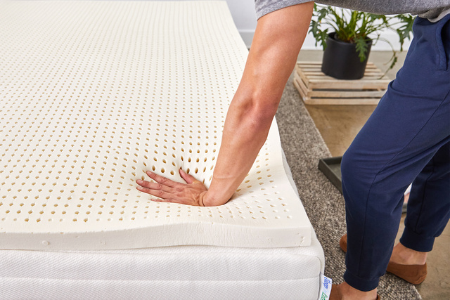 Hand pressing down on the mattress topper